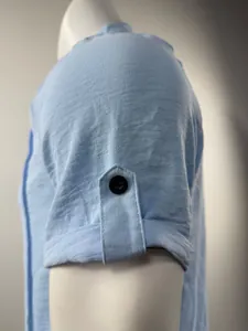Detailansicht eines hellblauen Henley-Hemdärmels mit Knopfleiste und feiner Stoffstruktur.