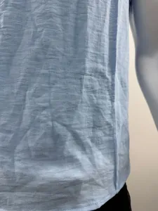 Detailaufnahme des hellblauen strukturierten Stoffes eines lässigen Henley-Shirts für Herren.