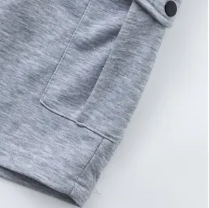 Close-up detail of grey cargo shorts showing fabric texture and snap button pocket