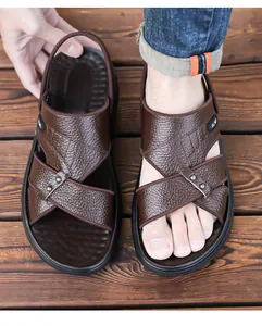 Detalle de sandalias de cuero marrón para hombre con tiras cruzadas y tachuelas de metal.