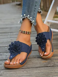 Detailansicht der marineblauen Keilsandalen mit einer großen dekorativen 3D-Blume