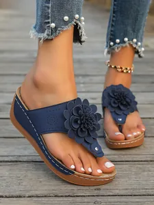Nahaufnahme der dunkelblauen Keilsandalette mit 3D-Blume und Kontrastnähten.