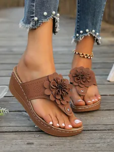 Detailansicht der braunen Damen Keilsandalen mit einer großen 3D Blumendekoration.