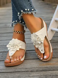 Nahaufnahme von Vintage-Keilsandalen mit Blumen für Damen auf Holzdeck-Hintergrund.