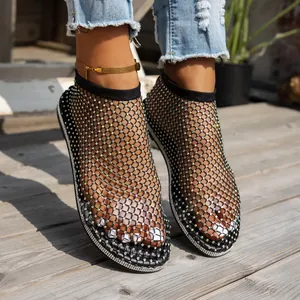 Dettaglio di sandali piatti in rete nera decorati con strass scintillanti e chic