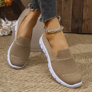 Detalle de mocasines de malla caqui transpirables para mujer con suelas blancas.