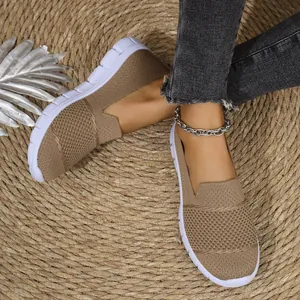 Primer plano de zapatos tipo slip-on de malla caqui transpirable para mujer, suelas blancas.
