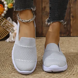 Vista detallada de mocasines de malla gris claro transpirables para mujer en alfombra rústica