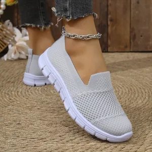 Primer plano de zapatillas de malla gris transpirable para mujer sobre alfombra de paja