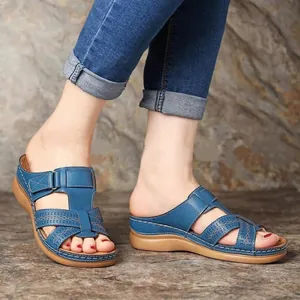 Detail shot of women's blue wedge sandals featuring elegant hollow cross straps on a model