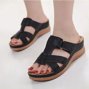 Comfortable women's black wedge sandals with laser-cut cross straps and tan sole.
