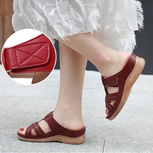 Close-up showing the adjustable hook-and-loop strap detail on a burgundy wedge sandal