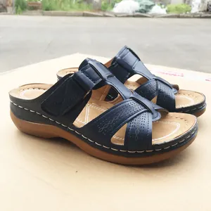 Side view detail of navy blue wedge sandals featuring cutout straps and white stitching