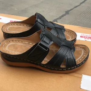 Detailed view of women's black wedge sandals featuring hollow cross straps and stitching.