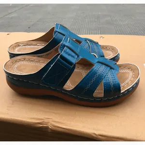 Side detail of blue wedge sandals with hollow cross straps and brown footbed