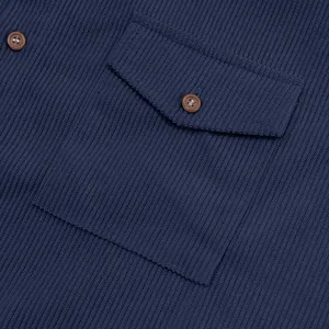 Detailed macro view showing the navy corduroy shirt pocket with brown button texture