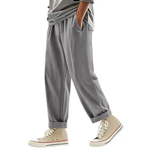 Detail view of men's grey linen-style wide-leg trousers paired with beige sneakers