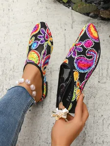 Detailansicht der lebhaften Paisley-Stickerei und des schwarzen Netzstoffs auf Sommerschuhen