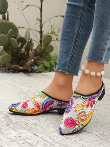 Detailansicht der stylischen, bunt bestickten Spitzen-Mesh-Mules an den Füßen des Models