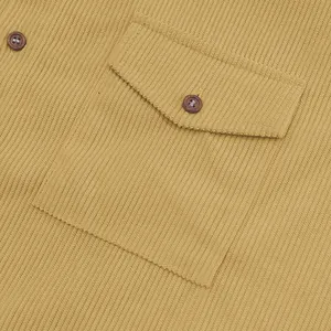 Macro view of corduroy texture and button pocket detail on mustard yellow shirt