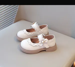 Détail de chaussures de princesse crème pour enfants avec dentelle et fleur de perle