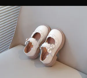 Gros plan sur des babies crème pour filles avec bordure en dentelle et nœud en perles.