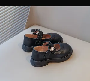 Détail de chaussures en cuir de princesse noires pour filles avec fleur de perle décorative