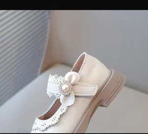 Détail de chaussures Mary Jane crème pour filles avec fleur en perles et dentelle.