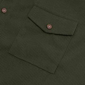 Close-up detail of a dark green corduroy shirt featuring a pocket and brown buttons.