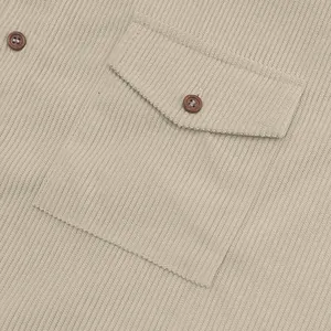 Close-up detail of a beige corduroy shirt pocket with wooden buttons
