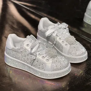 Detailansicht der weißen Strass-Sneaker mit Satinbändern und Perlenball-Deko