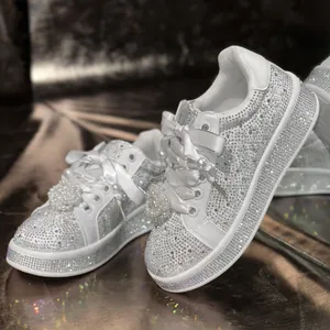 Detailansicht weißer Plateau-Sneaker mit vollem Strassbesatz und eleganter Perlblume
