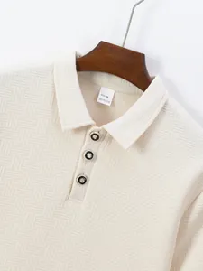 Close-up of cream textured jacquard polo shirt collar with metallic decorative buttons