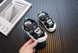 Nahaufnahme von schwarz-weißen Babysandalen mit Bären-Design in der Hand gehalten