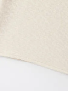 Close-up of cream jacquard fabric texture and hem stitching on polo shirt