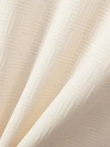 Close-up detail of premium cream white jacquard fabric texture on a summer polo shirt