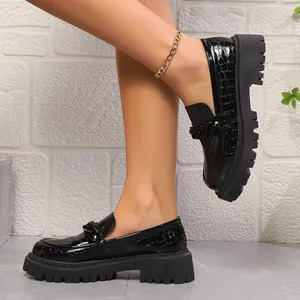 Détail de mocassins en cuir verni à motif crocodile noir avec semelle plateforme