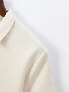 Close-up macro view of the intricate cream jacquard fabric texture on a men's polo shirt