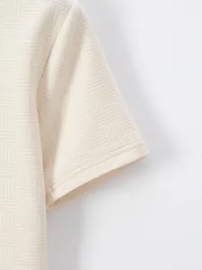 Close-up detail of cream men's polo shirt showing premium jacquard fabric texture