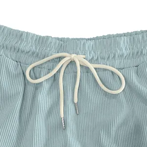 Dettaglio ravvicinato della coulisse crema e dell'elastico in vita di pantaloncini in velluto.