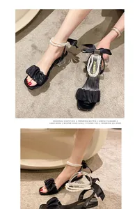 Detailed view of elegant black square toe sandals with pearl ankle straps and ruffle trim.