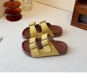 Détail de sandales style Birkenstock en daim jaune avec doubles boucles métalliques réglables