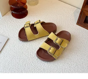 Vue détaillée de sandales en daim jaune à double boucle sur une surface blanche.