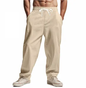 Detail view of men's loose beige linen trousers with drawstring waist and wide leg.