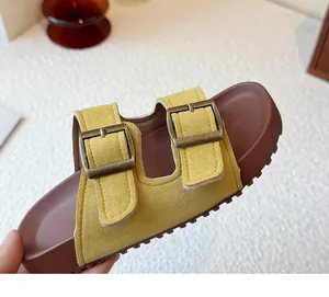 Sandale en daim jaune à double boucle avec assise plantaire marron et semelle épaisse.