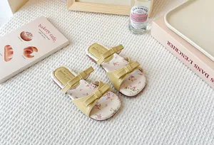 Vista detallada de sandalias planas para niñas con estampado floral y lazo amarillo