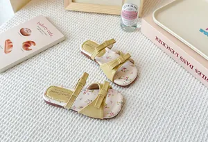 Detalle de sandalias amarillas para niña con lazos lindos y plantilla con flores frescas