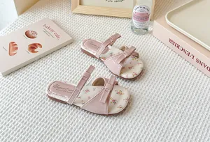 Vista de estilo de vida de sandalias rosas para niñas con suela floral y lazos.