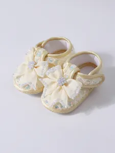 Detail of cream baby princess shoes featuring large bows and sparkling sequins decoration