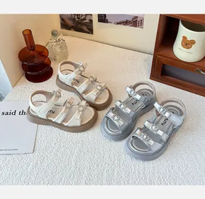 Vista detallada de sandalias de moda para niñas con hebillas de corazón en crema y plata.